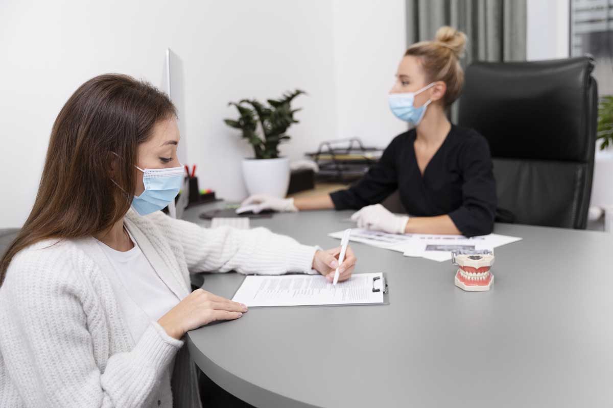 A patient signing some paperwork at a doctors practice.