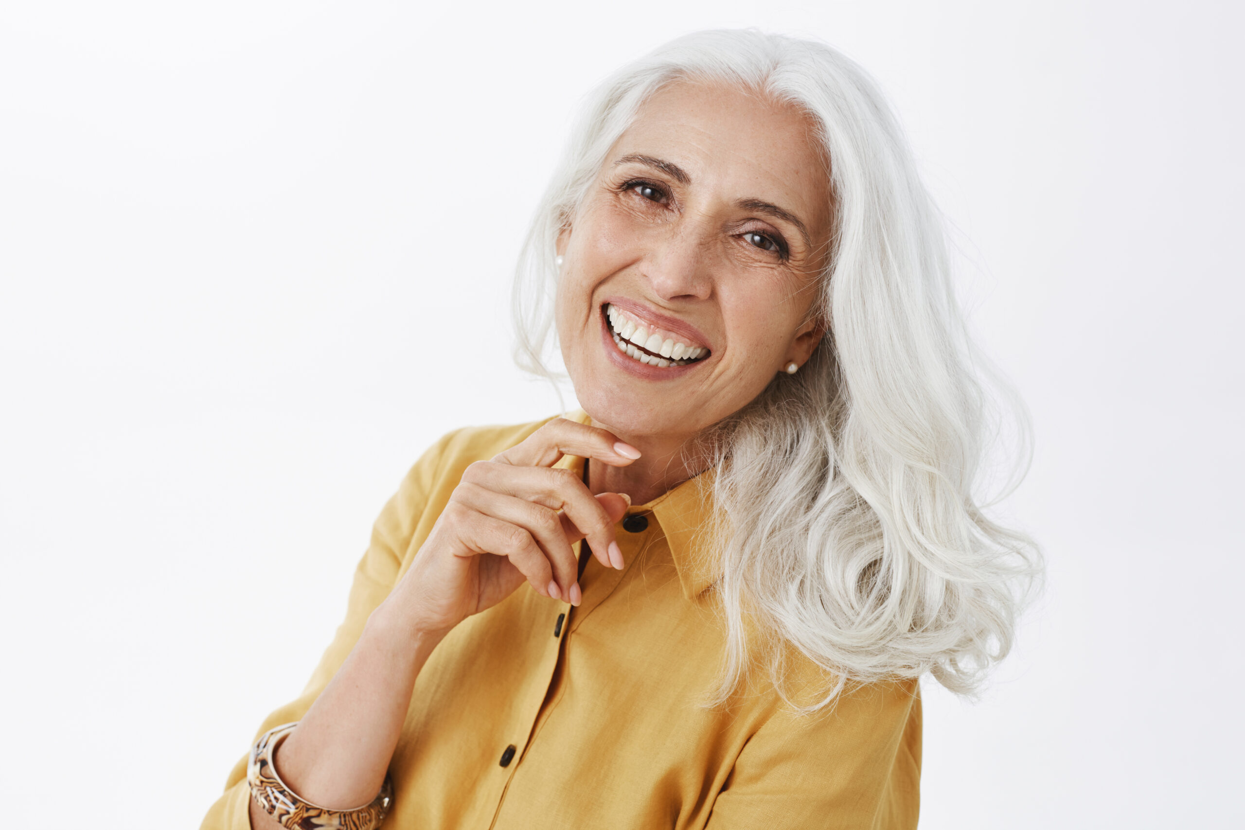 Portrait photo of a grey haired female, smiling into camera.